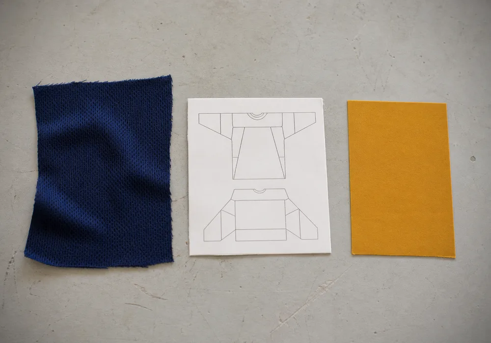 Three neutral reference items arranged for comparison: a fabric swatch, a panel diagram thumbnail, and a color reference chip on a plain work surface.