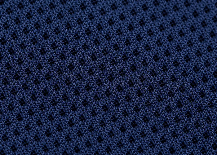 Close macro shot of air knit polyester fabric texture, open weave structure visible.