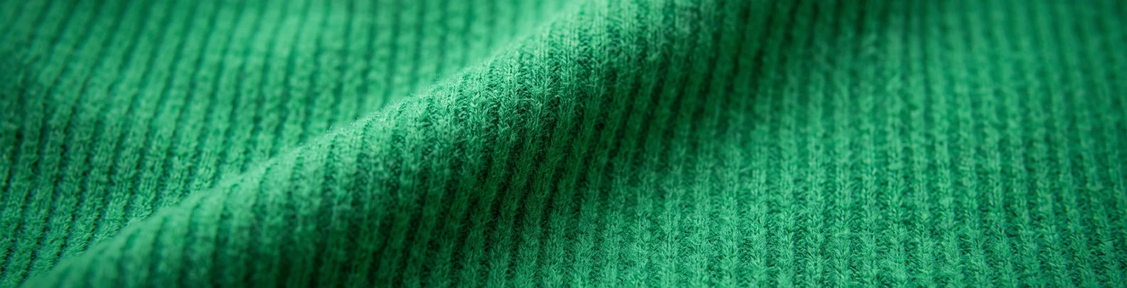 Close macro shot of undecorated ribbed fleece fabric in the Kelly Green colorway used for blank hockey pant shells.
