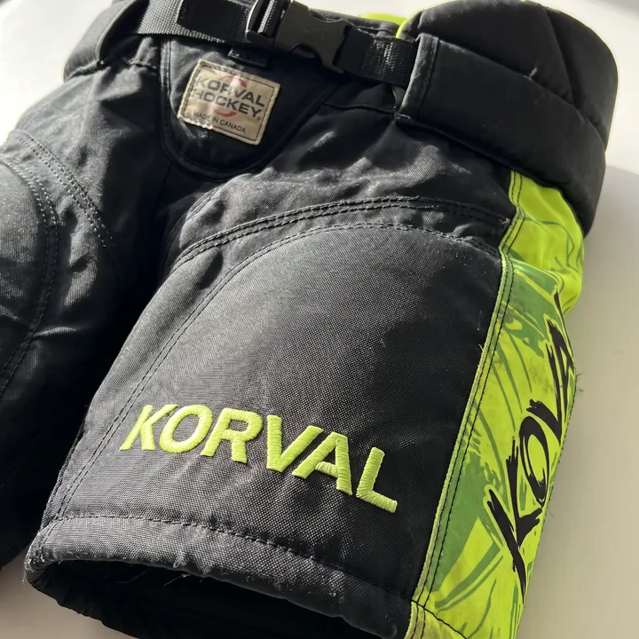 Close-up of a black pro-level pant front thigh with a lime sublimated side panel and embroidered brand mark