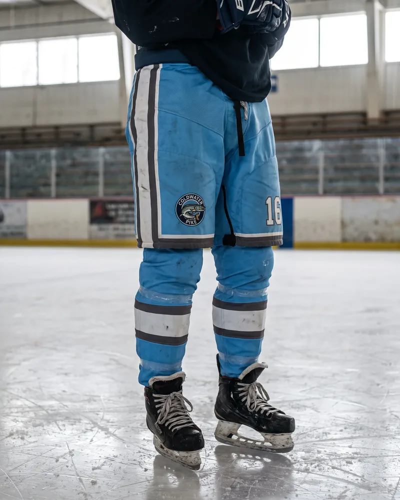 Teenage player in sky blue junior hockey pants with a pike crest, number 16 and an adjustable-length hem