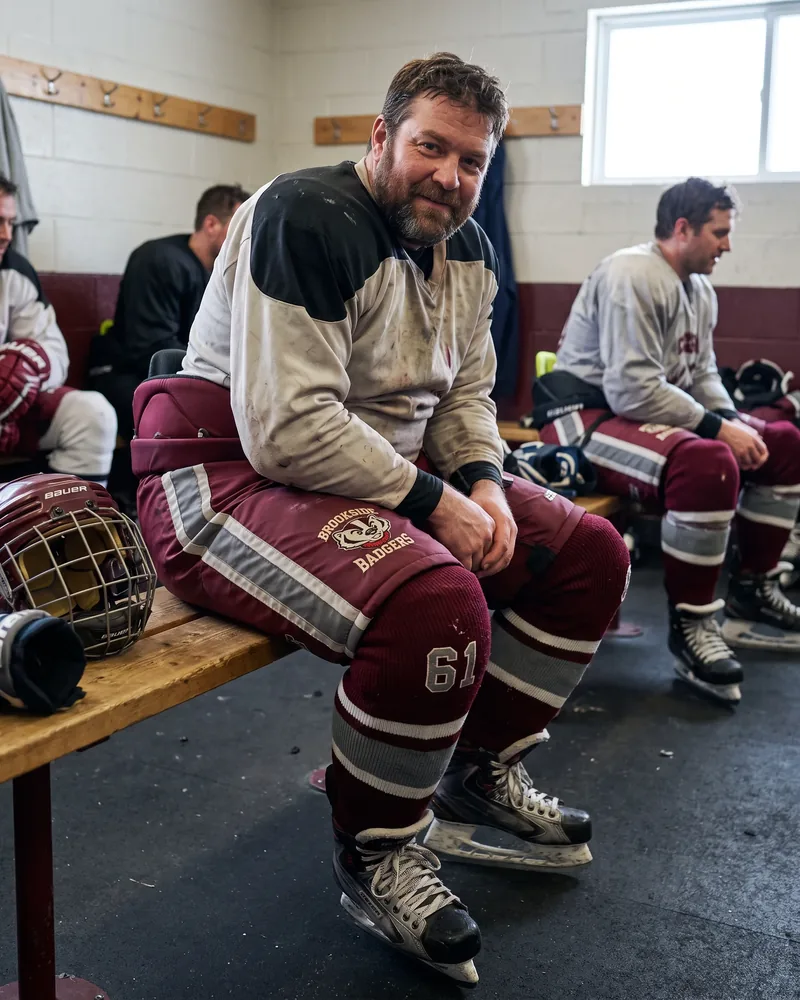 Adult league player on the bench in roomy maroon and grey classic-fit hockey pants