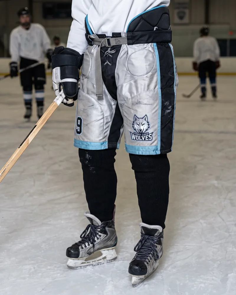 Junior player in silver and black tapered-fit hockey pants narrowing to the knee