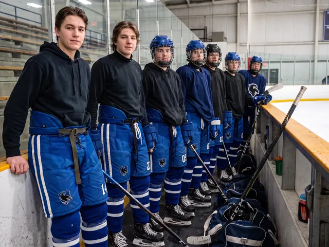 Junior roster lined up at the boards in royal blue hockey pants with numbers on the hip
