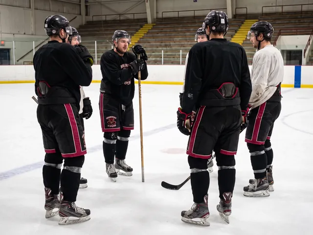 Semi-pro players at center ice in black and crimson pro-level hockey pants with matching crest placement