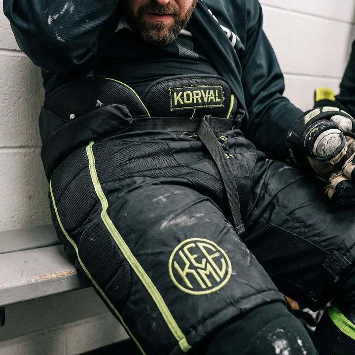 Athlete in black pro-level private label hockey pants with lime trim and a woven waistband label