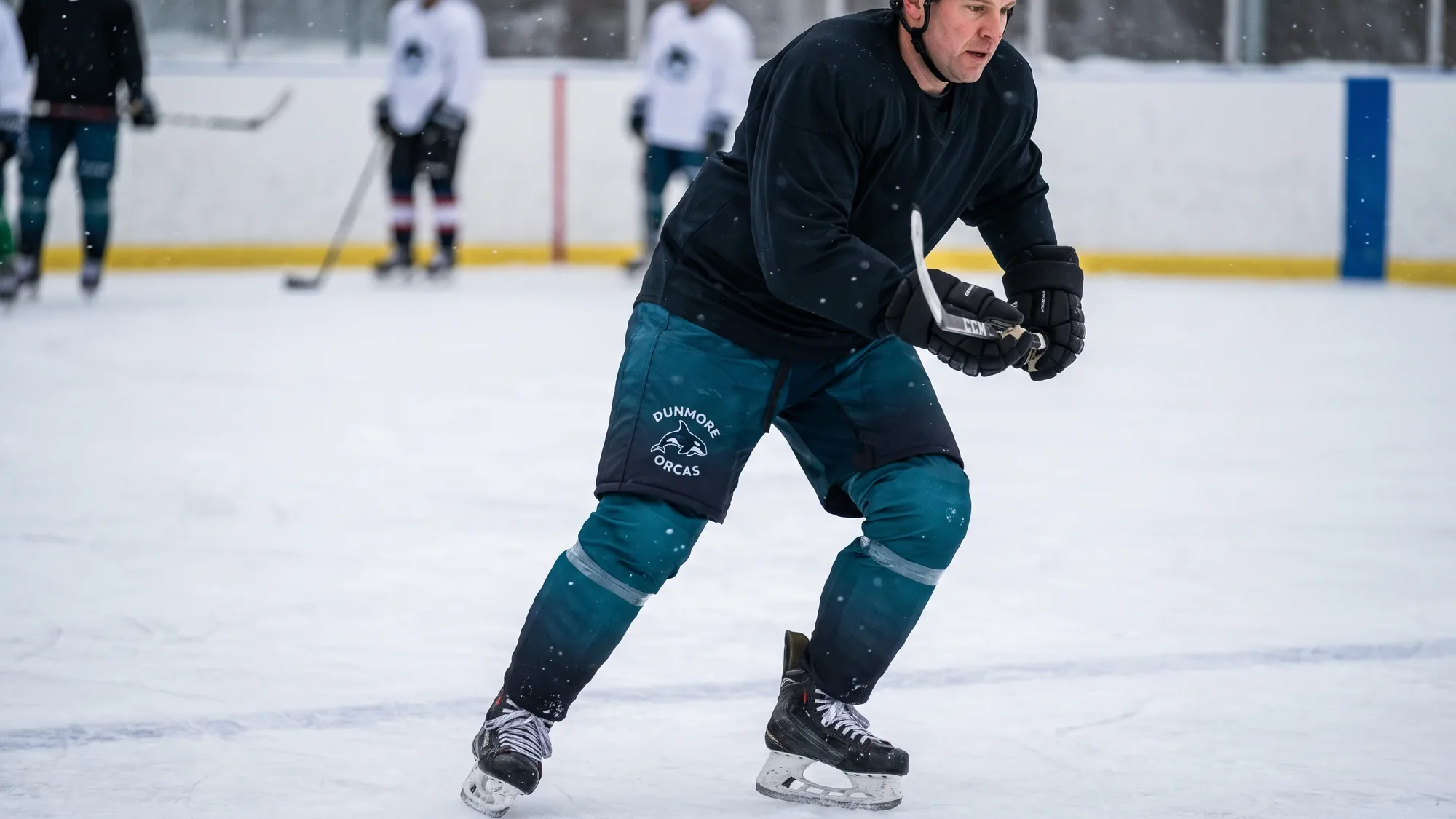 Player gliding in senior tapered hockey pants with a teal-to-black sublimated gradient and an embroidered orca crest on the hip