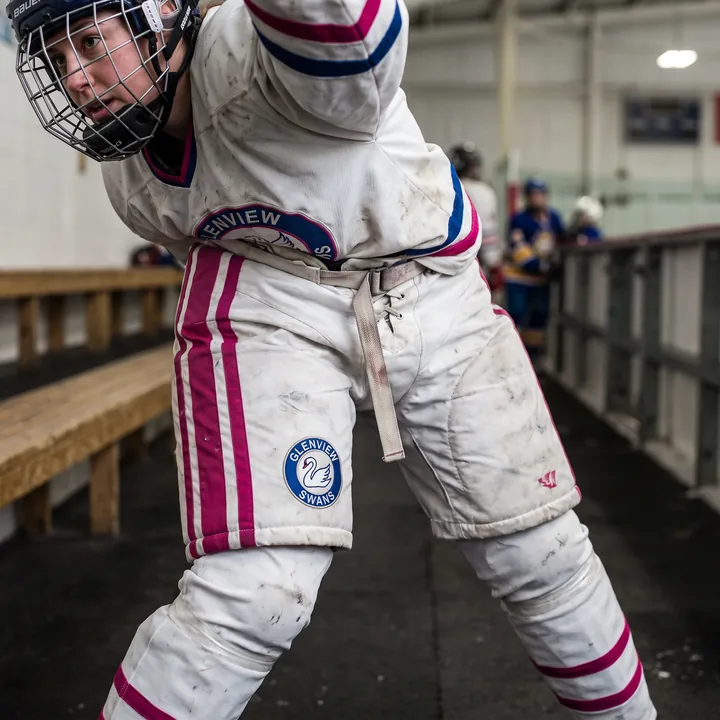 Player in white women's-fit hockey pants with fuchsia contrast stripes along the outer leg